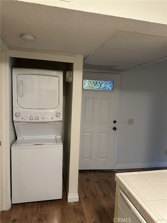 laundry area featuring dark hardwood / wood-style flooring and stacked washer / dryer