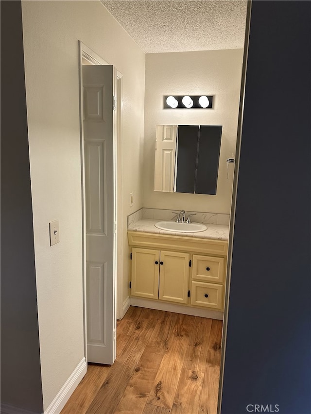 bathroom with wood-type flooring, vanity, and a textured ceiling