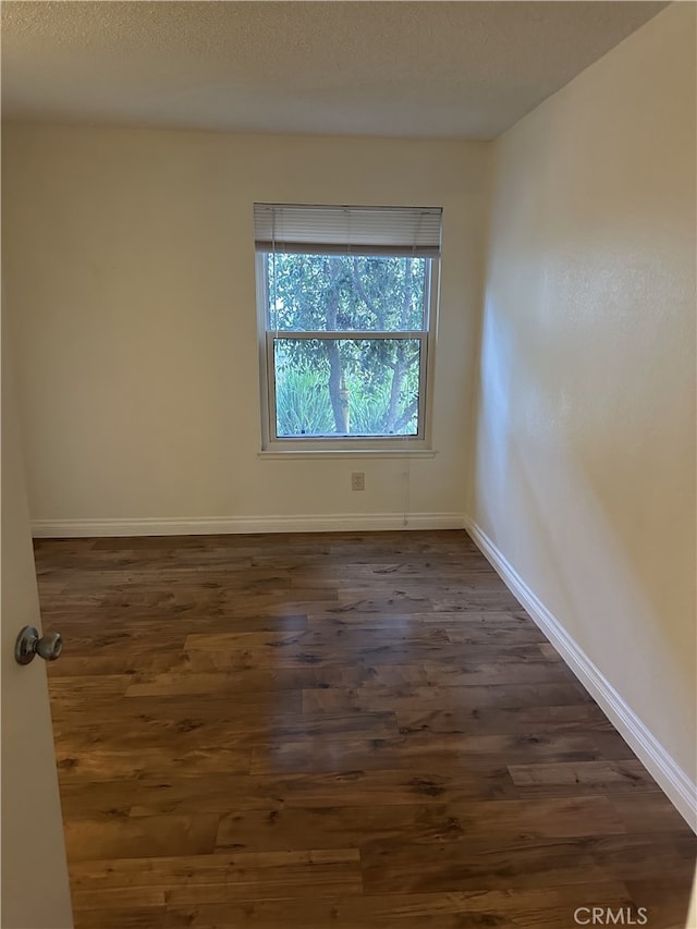 unfurnished room with dark wood-type flooring and a textured ceiling