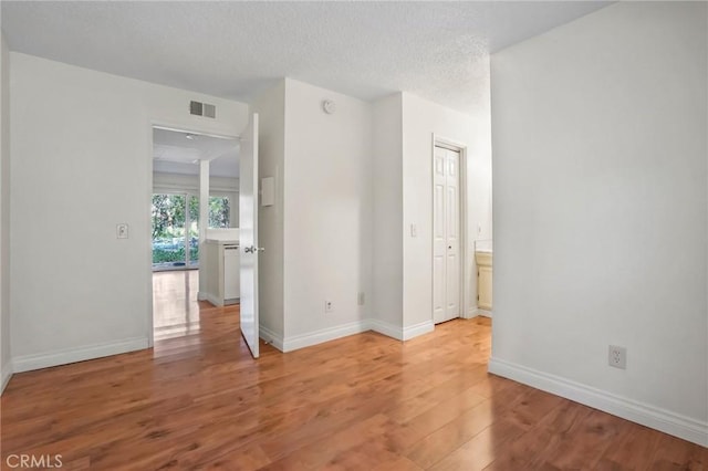 unfurnished room with hardwood / wood-style floors and a textured ceiling