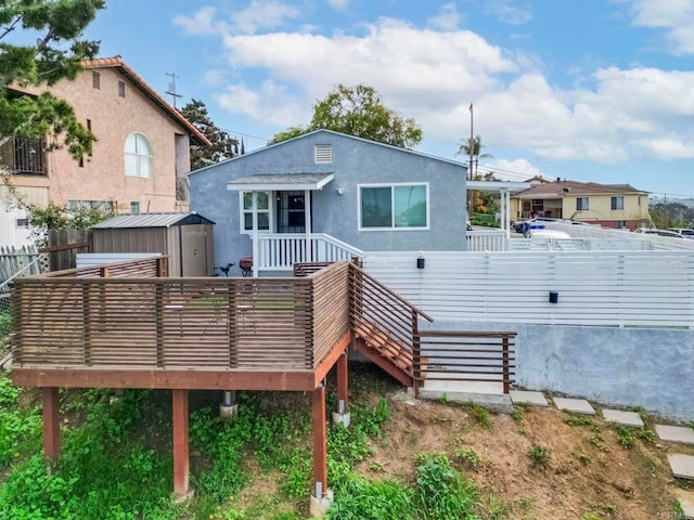 back of house with a shed and a deck