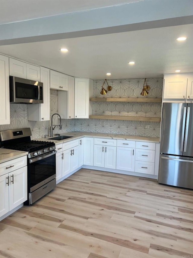 kitchen featuring sink, light hardwood / wood-style flooring, stainless steel appliances, and white cabinets