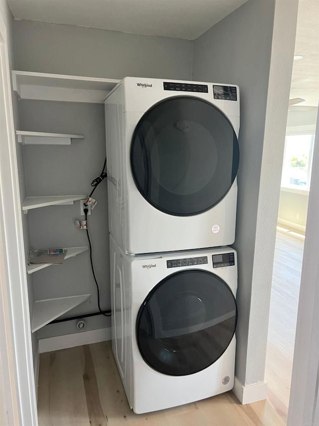 clothes washing area featuring stacked washer and clothes dryer and light wood-type flooring