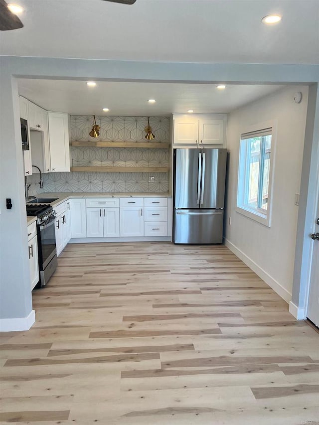 kitchen with backsplash, light hardwood / wood-style flooring, white cabinets, and appliances with stainless steel finishes