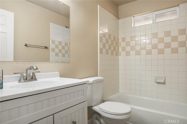 full bathroom featuring tiled shower / bath, vanity, and toilet