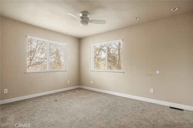 carpeted spare room featuring a healthy amount of sunlight and ceiling fan