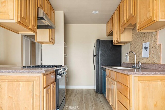 kitchen featuring gas stove, sink, backsplash, and light hardwood / wood-style flooring