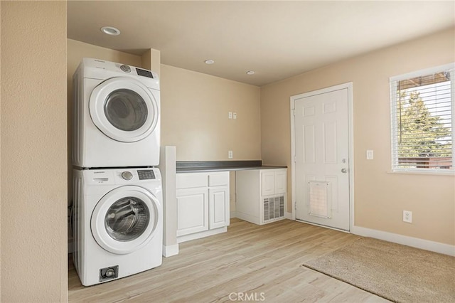 clothes washing area featuring light hardwood / wood-style floors and stacked washer / dryer