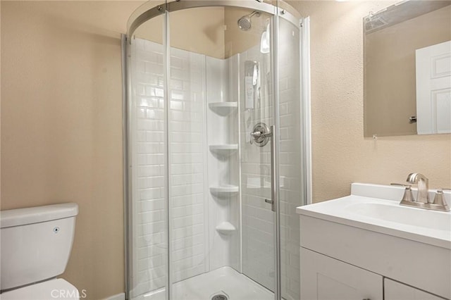 bathroom with a shower with door, vanity, and toilet