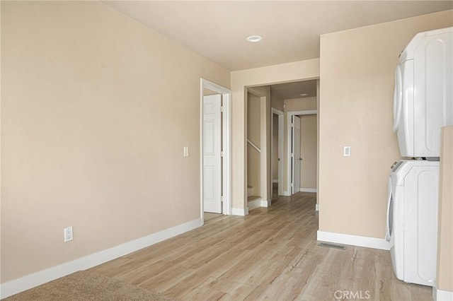 284 Davos Dr, Crestline, CA 92325 - unfurnished room featuring stacked washer and clothes dryer, baseboards, and light wood-style flooring