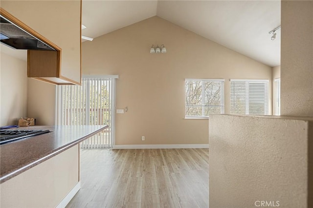 interior space with rail lighting, high vaulted ceiling, custom range hood, and light hardwood / wood-style flooring