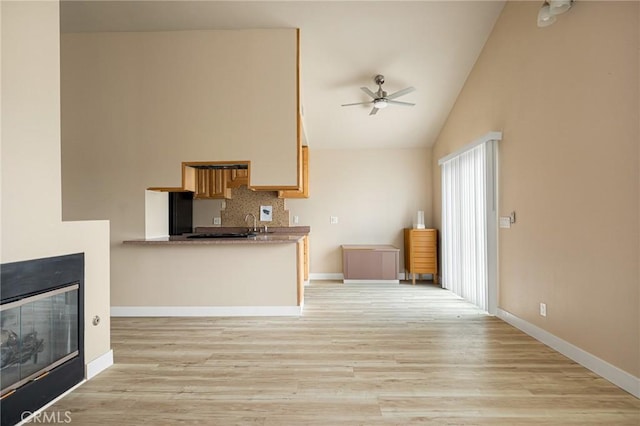 kitchen with ceiling fan, lofted ceiling, light hardwood / wood-style floors, and decorative backsplash