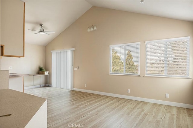 unfurnished living room featuring ceiling fan, high vaulted ceiling, and light wood-type flooring