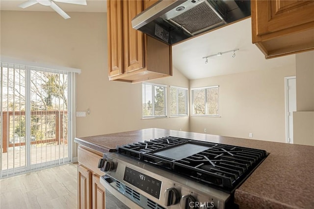 kitchen featuring rail lighting, lofted ceiling, exhaust hood, ceiling fan, and gas range