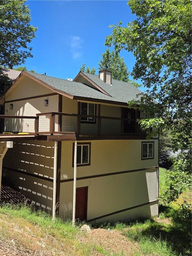 284 Davos Dr, Crestline, CA 92325 - back of property with a shingled roof, a chimney, and a balcony