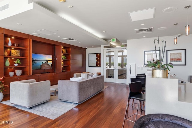 living room featuring dark wood-type flooring, built in features, and french doors