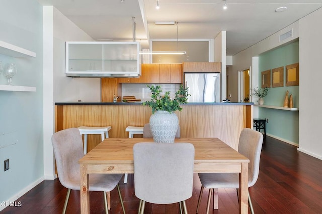 dining area with rail lighting and dark hardwood / wood-style floors