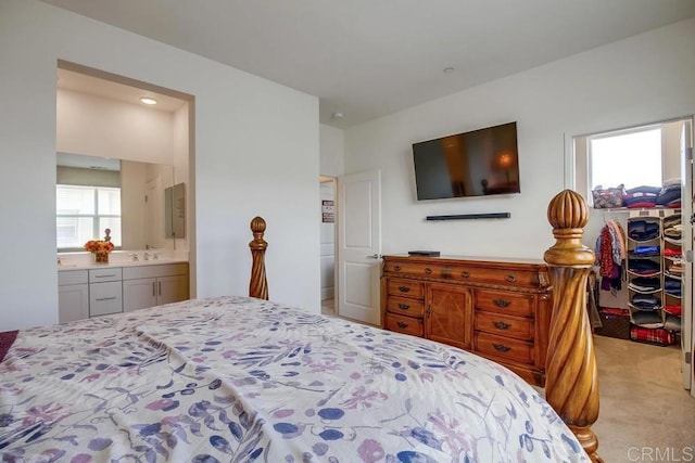 bedroom featuring connected bathroom, a spacious closet, and light colored carpet