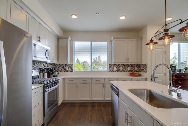 kitchen featuring sink, white cabinetry, dark hardwood / wood-style flooring, pendant lighting, and stainless steel appliances