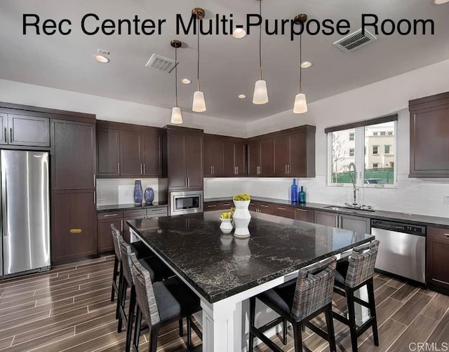 kitchen featuring a breakfast bar, sink, a center island, dark brown cabinetry, and stainless steel appliances