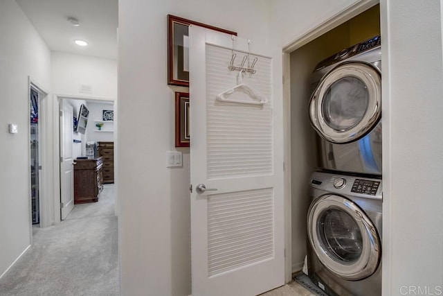 laundry area with light carpet and stacked washer / dryer