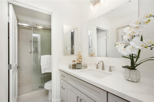 bathroom with vanity, a shower with door, and toilet