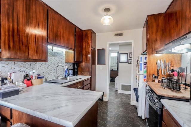 kitchen featuring sink, backsplash, white fridge, stainless steel range, and kitchen peninsula