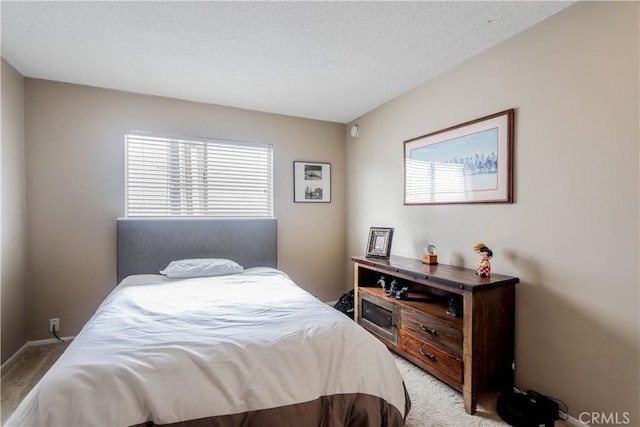 bedroom featuring light carpet and a textured ceiling