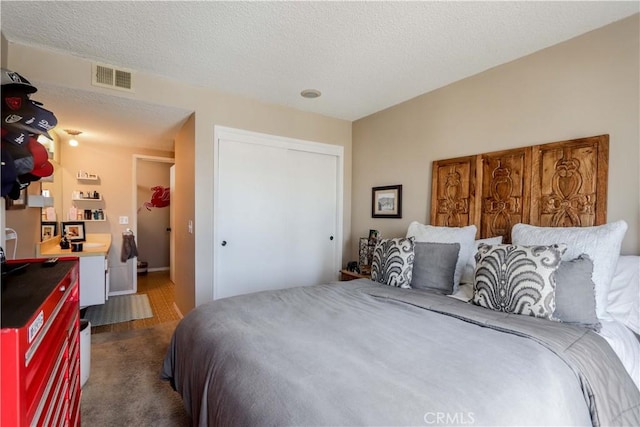 bedroom with a closet, dark carpet, and a textured ceiling