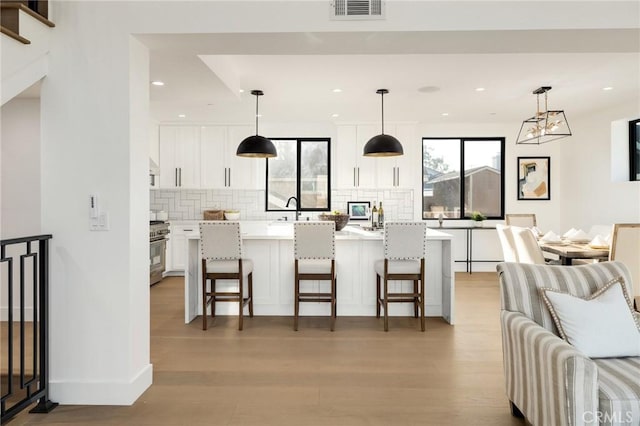 kitchen featuring pendant lighting, a breakfast bar area, a center island, and white cabinets