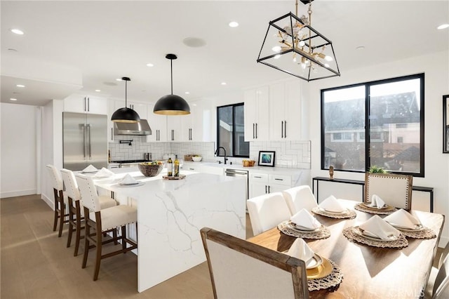 kitchen with tasteful backsplash, decorative light fixtures, a center island, stainless steel appliances, and white cabinets