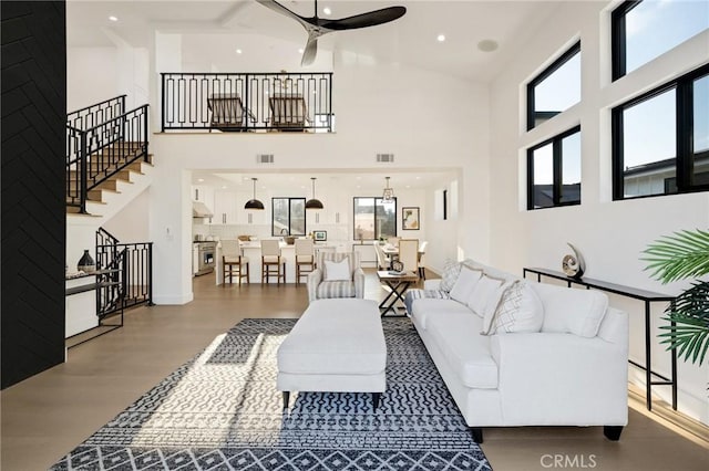 living room featuring ceiling fan, wood-type flooring, and a towering ceiling