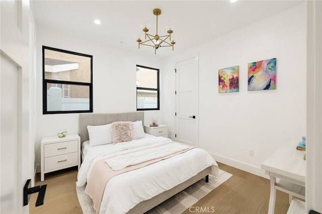 bedroom with a chandelier and light wood-type flooring