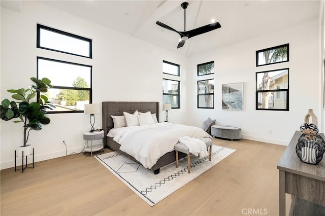 bedroom featuring hardwood / wood-style flooring, ceiling fan, and a high ceiling