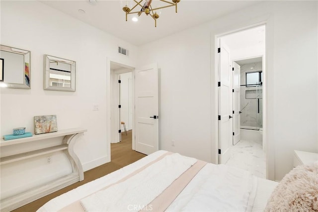 bedroom featuring ensuite bath and a chandelier