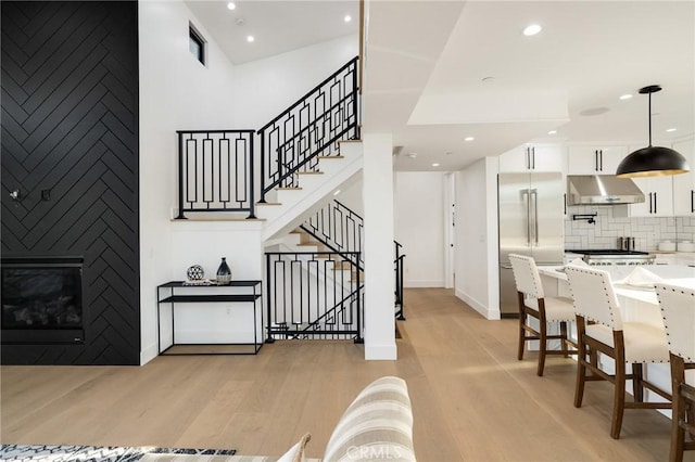 stairway featuring wood-type flooring, a towering ceiling, and a fireplace