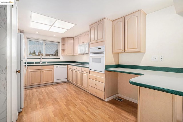 kitchen with sink, light brown cabinetry, white appliances, and light hardwood / wood-style floors