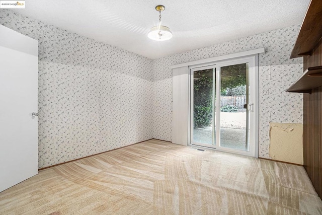 carpeted empty room featuring a textured ceiling