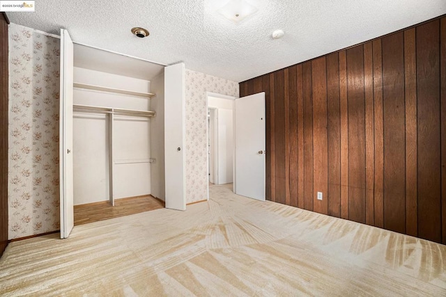 unfurnished bedroom with light colored carpet, a closet, and a textured ceiling