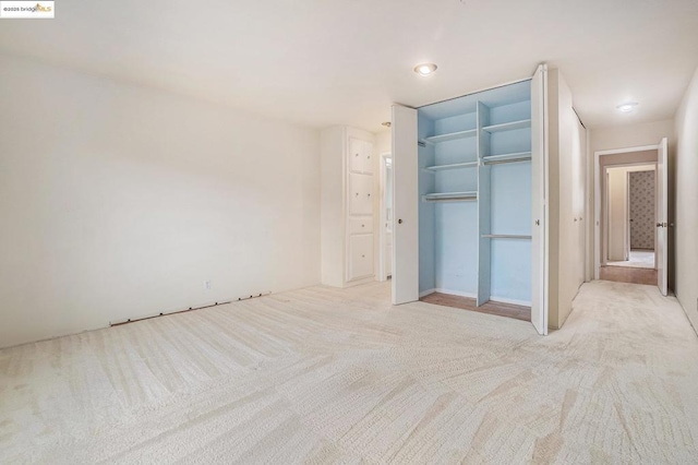 unfurnished bedroom featuring light colored carpet and a closet