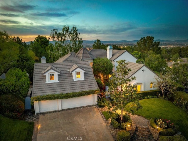 new england style home featuring a garage, a chimney, concrete driveway, and a front yard