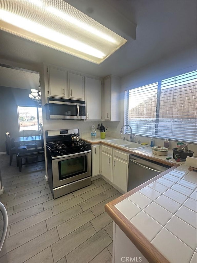 kitchen featuring stainless steel appliances, tile counters, sink, and plenty of natural light