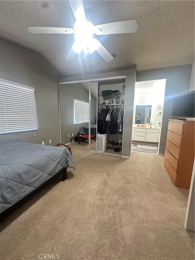 carpeted bedroom with vaulted ceiling, a textured ceiling, and a closet