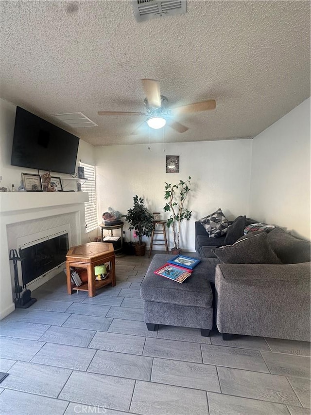 living room featuring ceiling fan and a textured ceiling