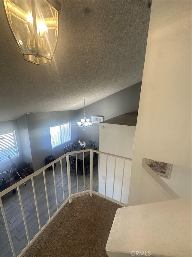 interior space with an inviting chandelier, carpet, and a textured ceiling