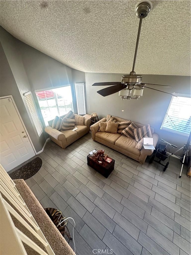 unfurnished living room featuring ceiling fan, lofted ceiling, and a textured ceiling