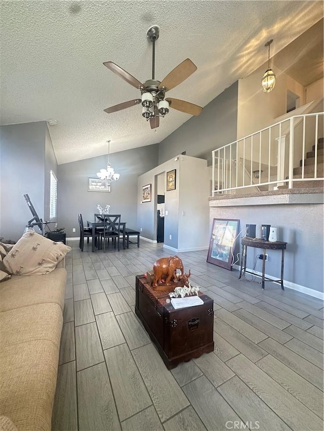 living room featuring ceiling fan with notable chandelier, vaulted ceiling, and a textured ceiling