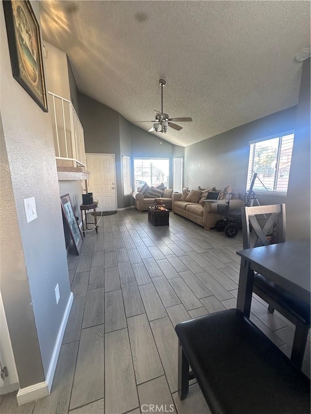 living room featuring lofted ceiling, a textured ceiling, and ceiling fan