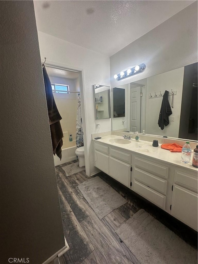 full bathroom featuring toilet, wood-type flooring, a textured ceiling, vanity, and shower / bathtub combination with curtain