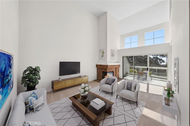 living area with a high ceiling and a glass covered fireplace